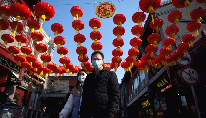 People walking under traditional Chinese lanterns along an alley in Beijing ahead of the Lunar New Year. AFP