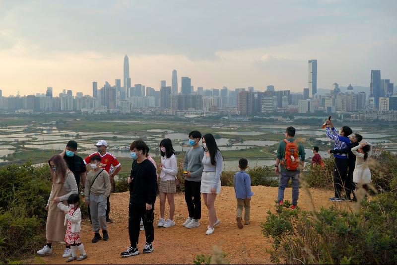 香港民众戴口罩於大年初二登上界乎香港与深圳边境的 山头，眺望深圳市的天际线。（美联社照片）