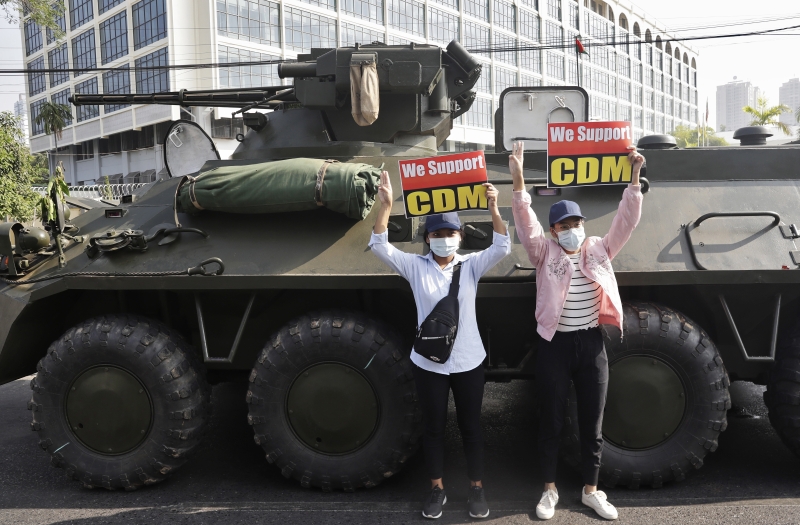 在仰光中央银行外，示威者站在装甲车旁，举著“我们支持公民不服从运动”的标语。（图：欧新社）