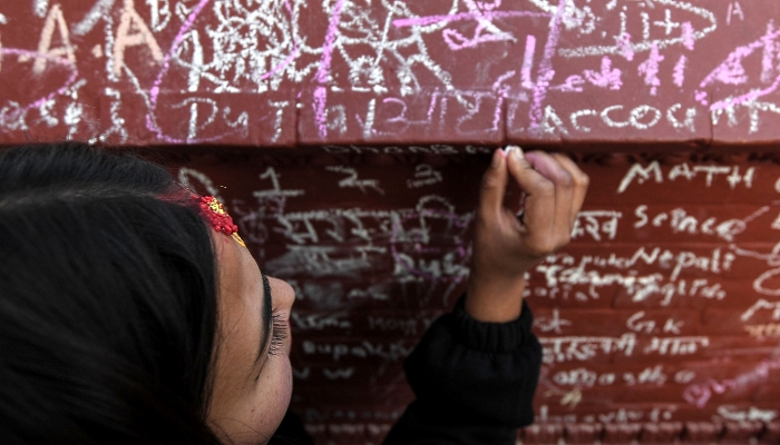 People writing messages with chalk on a wall at the Saraswati Temple  in Kathmandu, Nepal, on the occasion of the Hindu festival of 'Basanta Panchami'. AFP