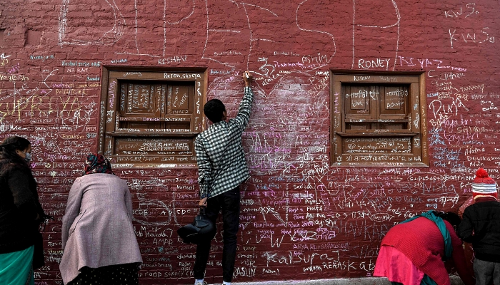 People writing messages with chalk on a wall at the Saraswati Temple  in Kathmandu, Nepal, on the occasion of the Hindu festival of 'Basanta Panchami'. AFP