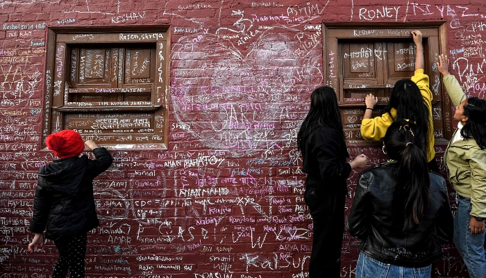 People writing messages with chalk on a wall at the Saraswati Temple  in Kathmandu, Nepal, on the occasion of the Hindu festival of 'Basanta Panchami'. AFP