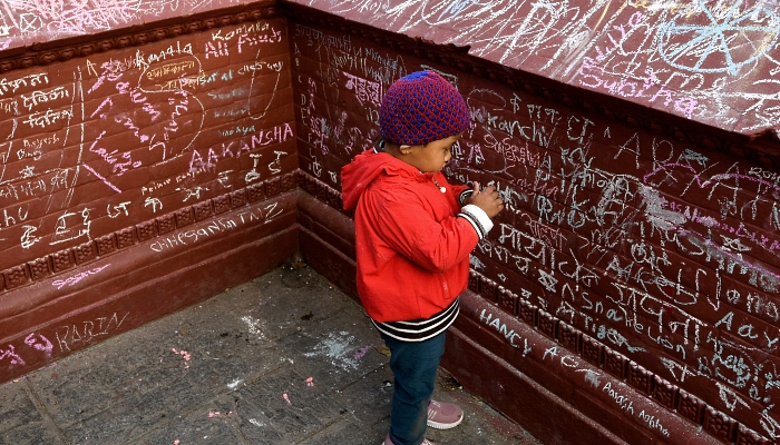 People writing messages with chalk on a wall at the Saraswati Temple  in Kathmandu, Nepal, on the occasion of the Hindu festival of 'Basanta Panchami'. AFP