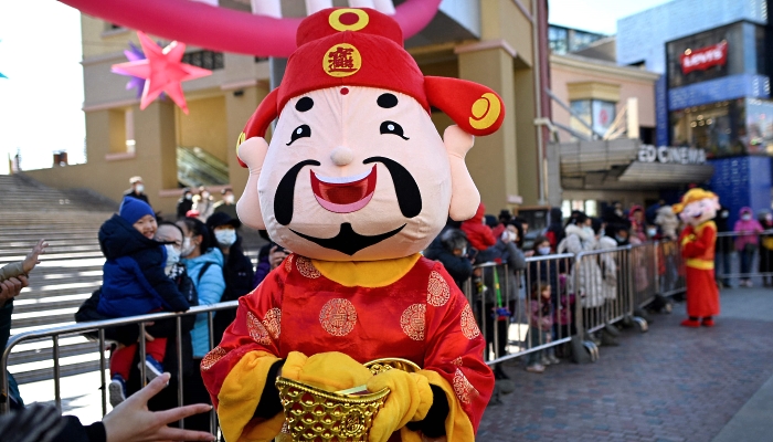 A participant dressed in a God of Prosperity costume hands out gifts to people outside a mall in Beijing on the fifth day of Lunar New Year. AFP