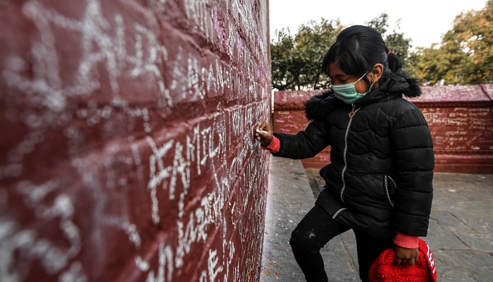 People writing messages with chalk on a wall at the Saraswati Temple  in Kathmandu, Nepal, on the occasion of the Hindu festival of 'Basanta Panchami'. AFP