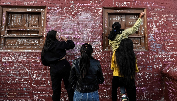 People writing messages with chalk on a wall at the Saraswati Temple  in Kathmandu, Nepal, on the occasion of the Hindu festival of 'Basanta Panchami'. AFP