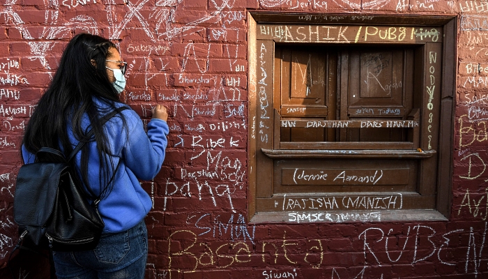 People writing messages with chalk on a wall at the Saraswati Temple  in Kathmandu, Nepal, on the occasion of the Hindu festival of 'Basanta Panchami'. AFP