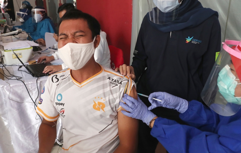 在塔纳阿邦成衣批发市场，一名男子接种疫苖时，紧闭眼睛，显得紧张。（图：美联社）