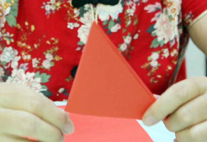 步骤四：再把中间对折，折成一个更小的三角形。