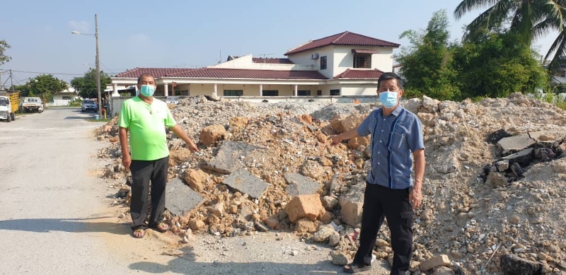 潘国全（左）和巴生园居协理事何国文视察电讯公司承包商倾倒在花园区私人空地的沙石。