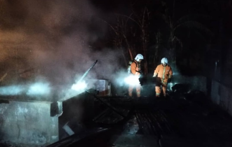 消拯人员在油棕园着火房屋灭火后，进入火场查看是否尚存未灭火种。