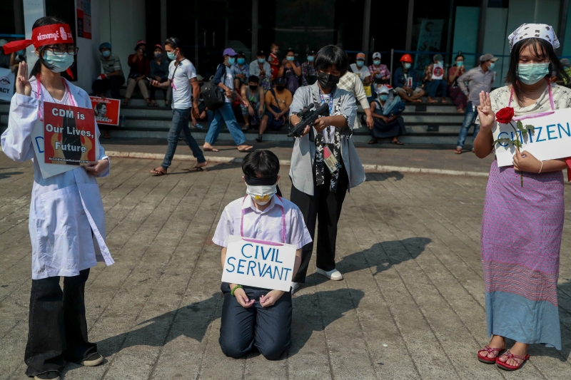 反政变示威者演示公务员在军方枪口下被迫工作的困境。（图：美联社）