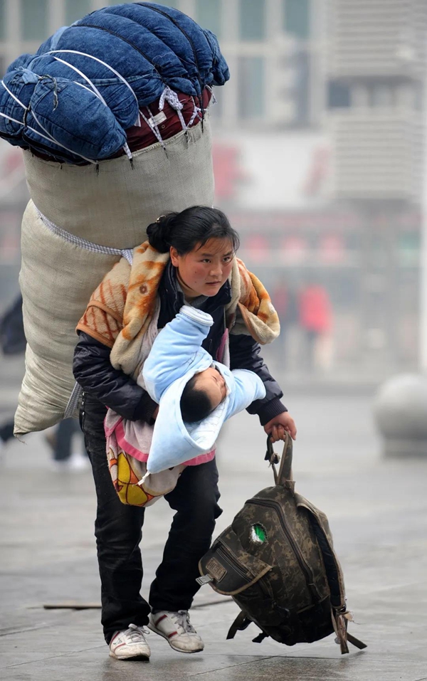 11年前，年轻女子巴木背着巨大、沉重，露出被褥的行囊，极力要挺起被压弯的身躯，一手抱着宝宝，另一手拎着背包，赶着前往车站。她是中国10年脱贫的1亿人口中的其中一人，11年后，当年拍下这张照片的新华社记者找到了她，她目前的生活已大大改善了。（图：新华社档案照）