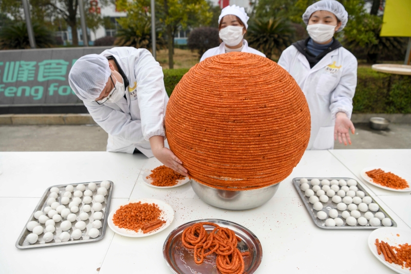 中国湖南省岳阳市平江县的辣条厂的工人们在厂区内制作“辣条元宵”。图为工人们用面团与辣条围成一个直径近1米的巨型元宵。（图：中新社）