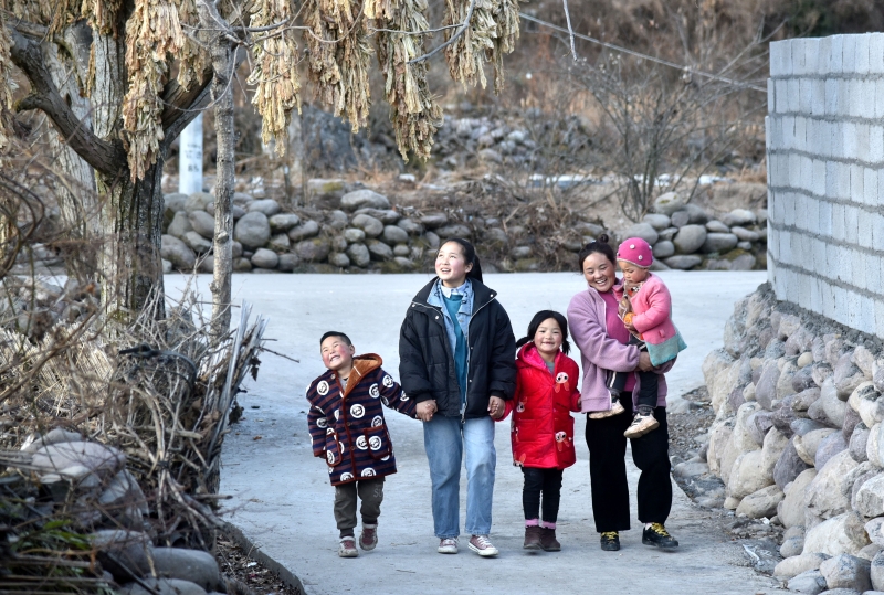 今年1月22日，巴木玉布木（右1）和孩子们行走在桃园村修建好的水泥路上。（图：新华社）