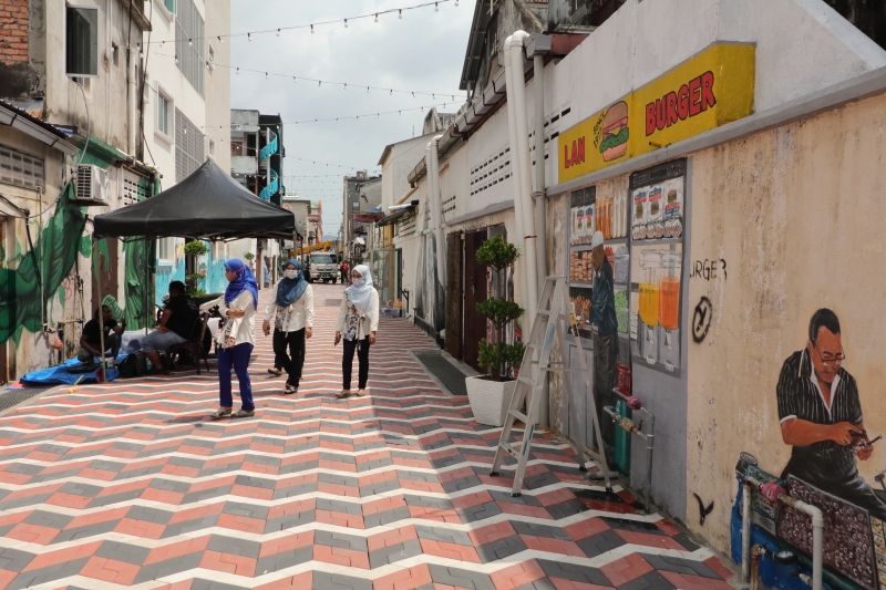 民众经过美化中的关丹大街后巷也放慢脚步欣赏壁画。
