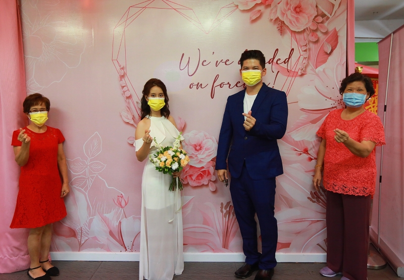 一对新人完成婚姻注册仪式后，与双方母亲在保持人身距离的情况下合照。