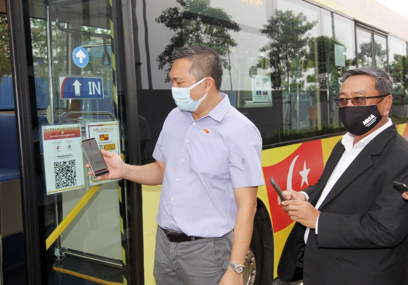 黄思汉（左）向大众示范上巴士前使用“扫描搭车”系统。右为哈利斯。