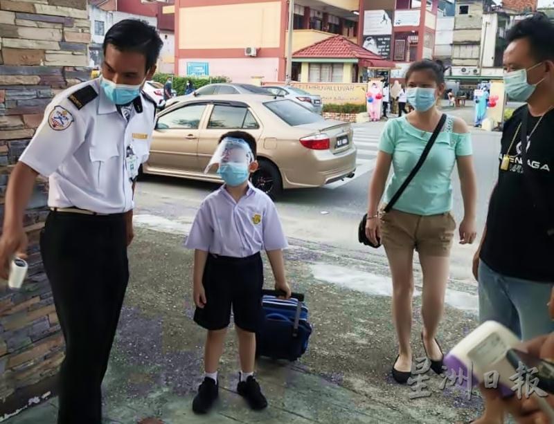 家长为这名学生戴上口罩、脸罩，让孩子全副武装走入校园。
