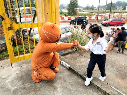 在砂拉越石隆门县的短廊中华公学，校长李猷列以熊熊装扮，和到校的小学生以击拳的方式打招呼。