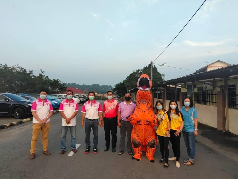 萧昭南（左四）率恐龙吉祥物和校内董事部、家协理事在校门口迎接新生。