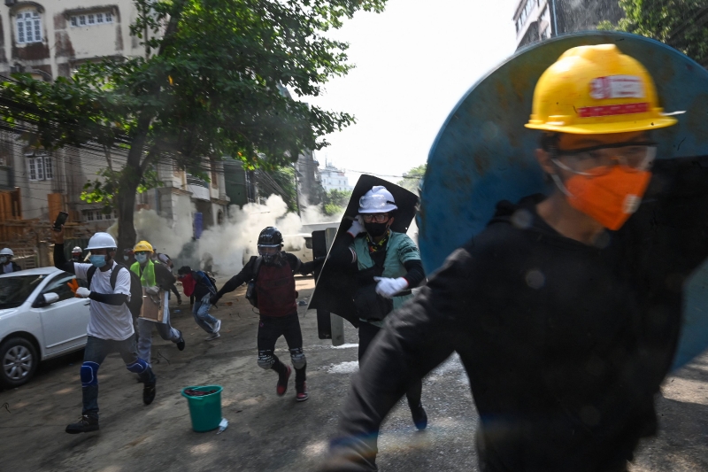 示威者躲避警方的催泪弹。（图：法新社）