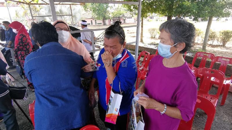 右起林丽明（70岁）、江志萍（62岁）及她们的院友与看护员拥抱道别，忍不住抽泣。