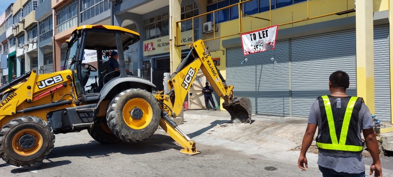 由于店主迟迟没有拆除店前沟渠违建洋灰盖，市议会只好调动挖泥机进行清拆工作。