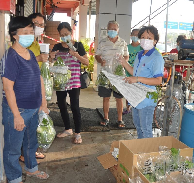 威南洗肾中心行政经理张秀珍（右一）在中心大门口派新鲜蔬菜给居民。