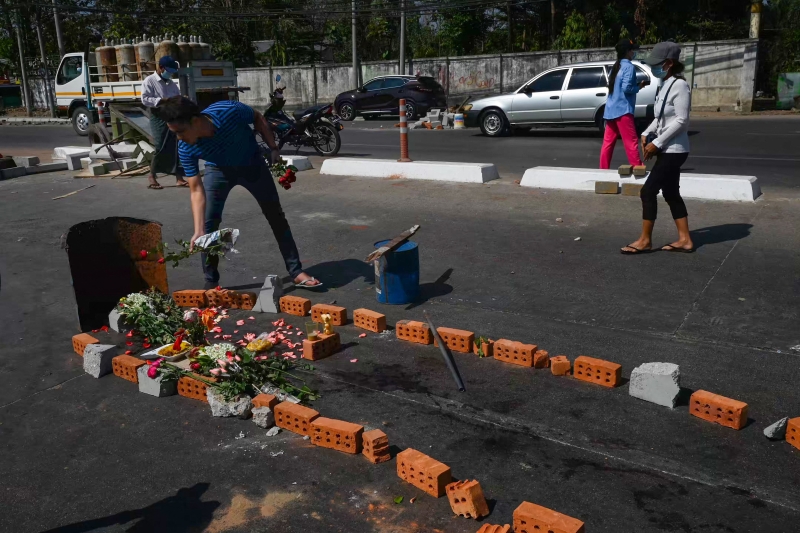 一名男子在仰光马路上为此前遇难的5名示威者献上鲜花。