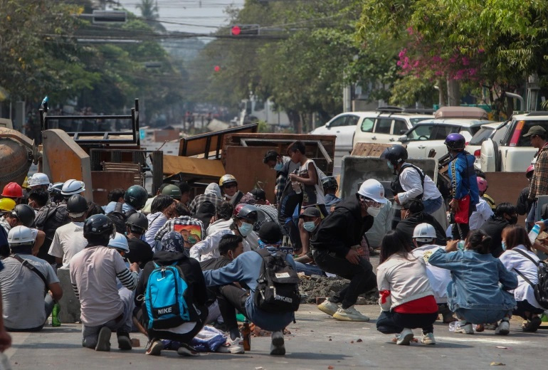 在曼德勒，军警武力驱散示威者后，民众躲在临时路障后以策安全。