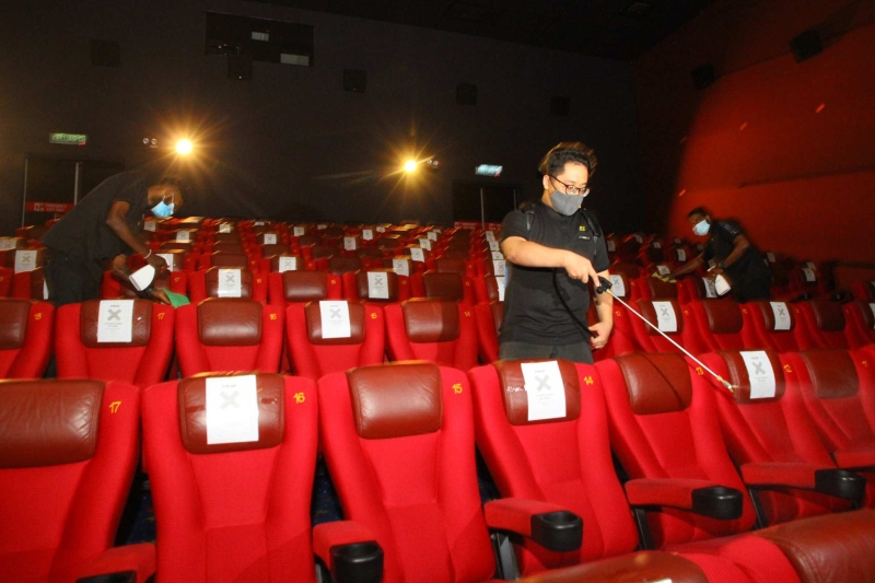 电影院员工擦拭座椅，并喷洒消毒水对整个放映厅进行消毒。