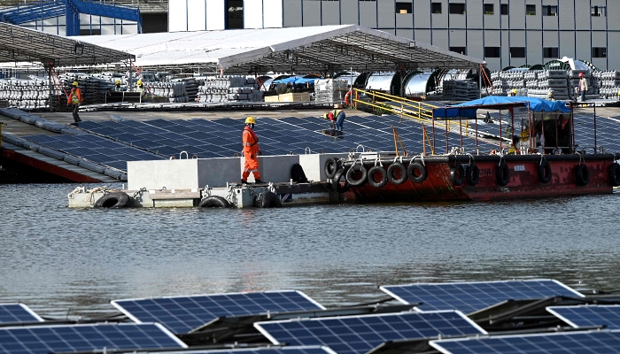 Workers on a barge transporting sinkers to build a floating solar power farm on Tengeh Reservoir in Singapore. AFP