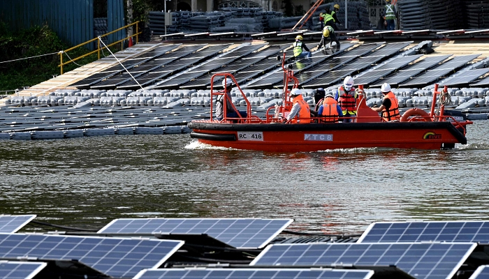Workers heading out in a boat to build a floating solar power farm on Tengeh Reservoir in Singapore. AFP