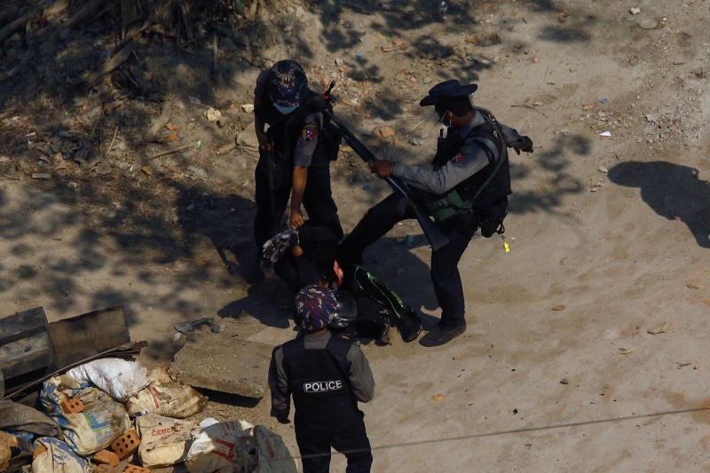 数名警员手持枪枝，在仰光围殴拘捕一名示威者。（图：法新社）