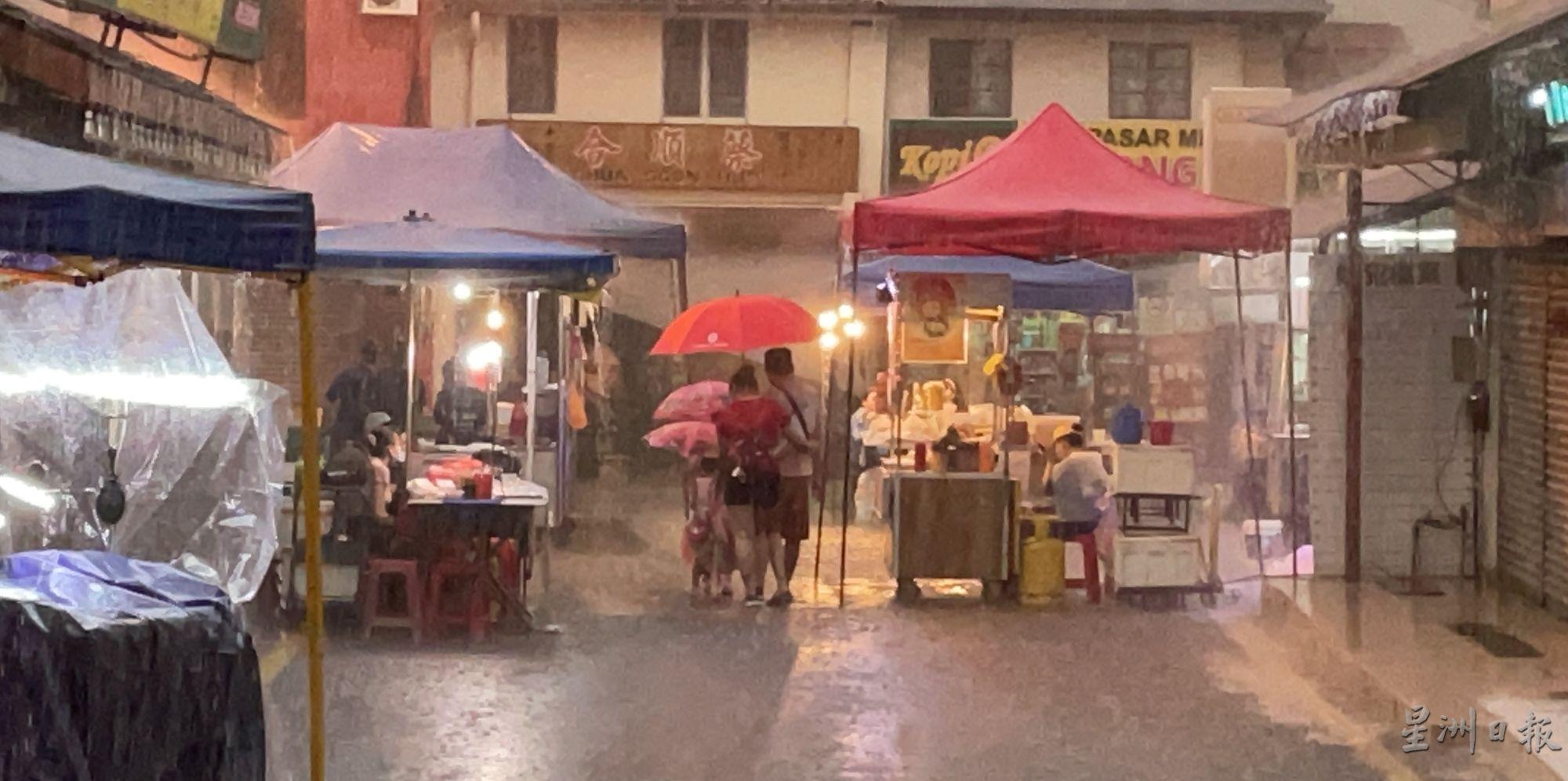 夜市开档遇到下雨，但仍可看到游客撑伞浏览的身影。