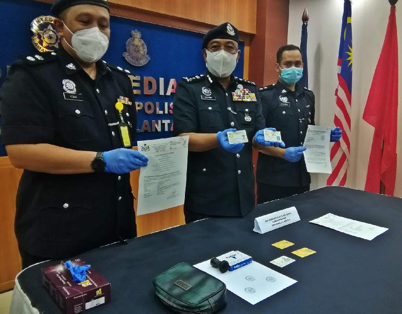 沙菲安玛末（中）与警官展示警方所起获的伪造文件、证件和印章，揭发假拿督勾当。

