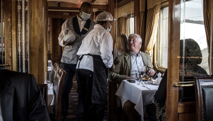 Esther Ndhlovu (C), the head chef onboard the Blue Train, talks to passengers as the train approaches the Karoo area. AFP