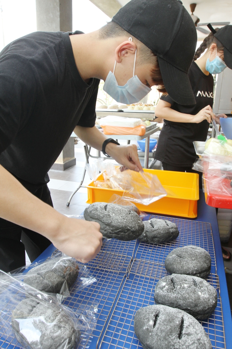 学徒将新鲜出炉的竹炭面包安装进包装纸内，准备出售。