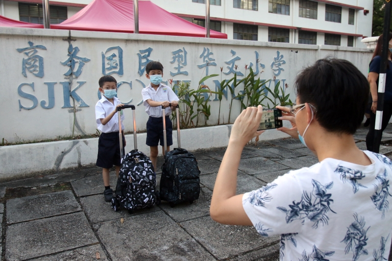 一名家长在为孩子在校外拍照以做留念。（图：星洲日报）