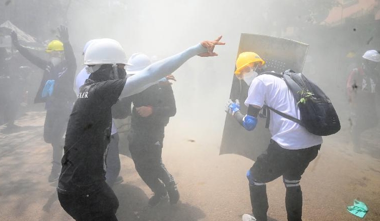 Protesters react after tear gas is fired by police during a demonstration against the military coup in Yangon. AFP Protesters react after tear gas is fired by police during a demonstration against the military coup in Yangon. AFP