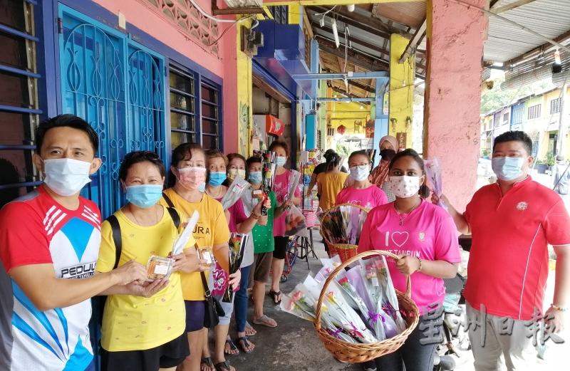 吴俊益（左一）到武吉淡汶老街送康乃馨及红龟糕派发给淡汶老街的妇女们，右起周键諵村和胡萍聚村长等陪同。