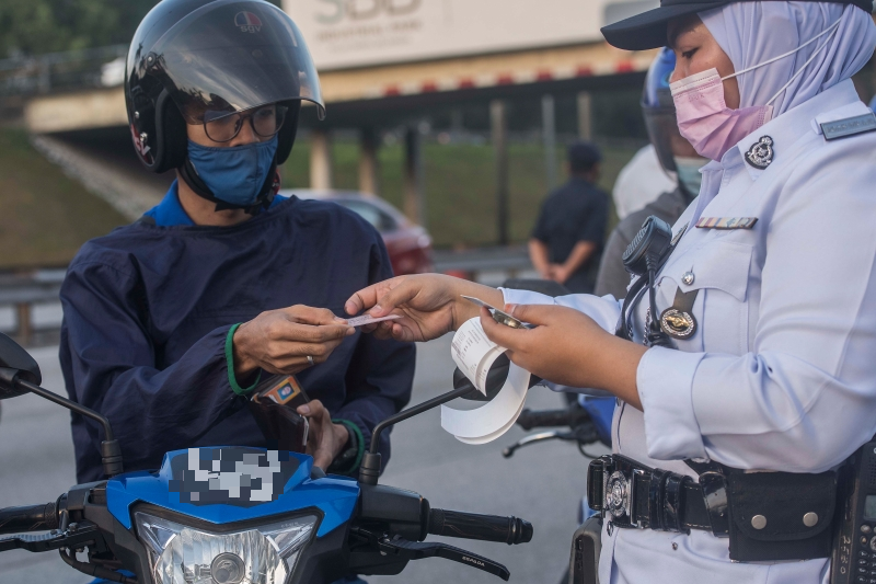 其中一名女交警向违规的摩托车骑士开罚单。