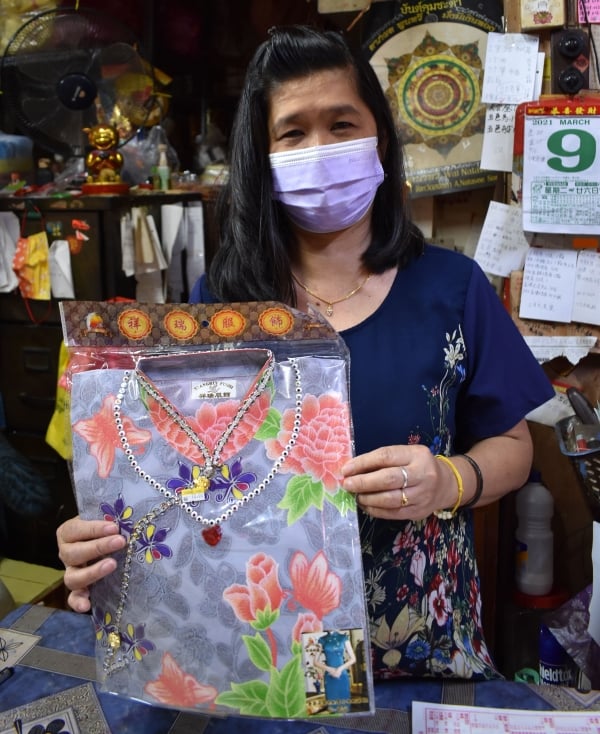 李凤琼展示其中一款由中国进口的高贵旗袍纸扎品。