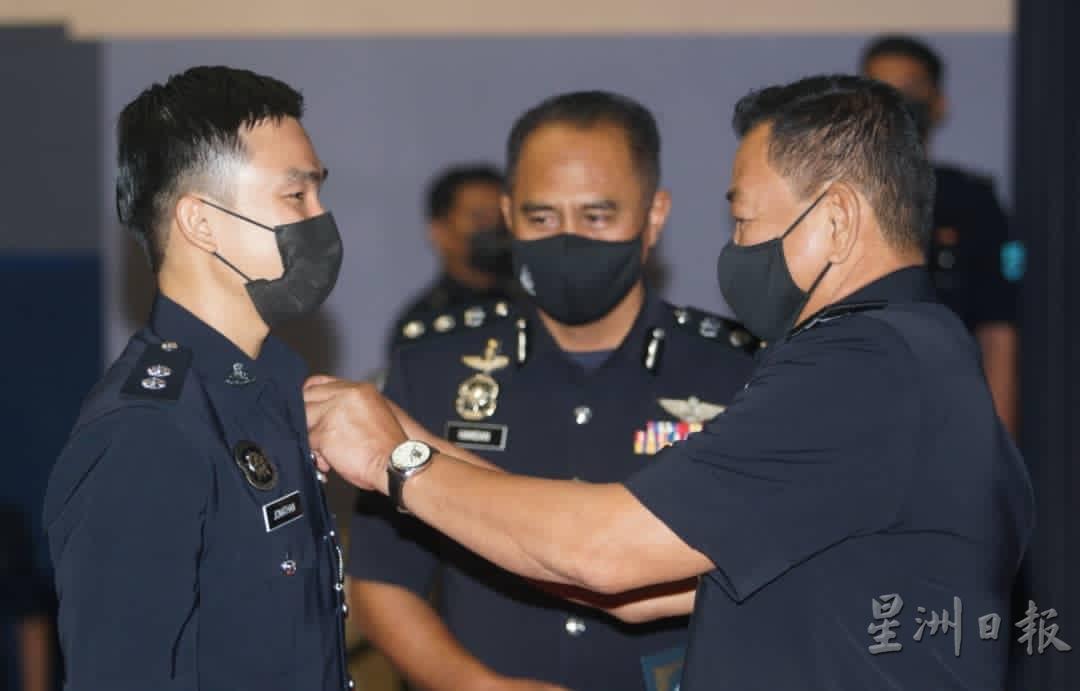 阿都哈密（右）为完成飞行员训练的警员莫镇聪别上飞翼肩章。