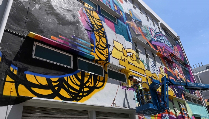 Urban artist Antz spray paints a murals on the wall of a building in Singapore. AFP