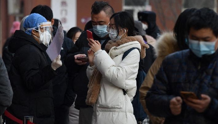 People scanning a QR code to display their health status as they line up to be tested for Covid-19 in Beijing. AFP