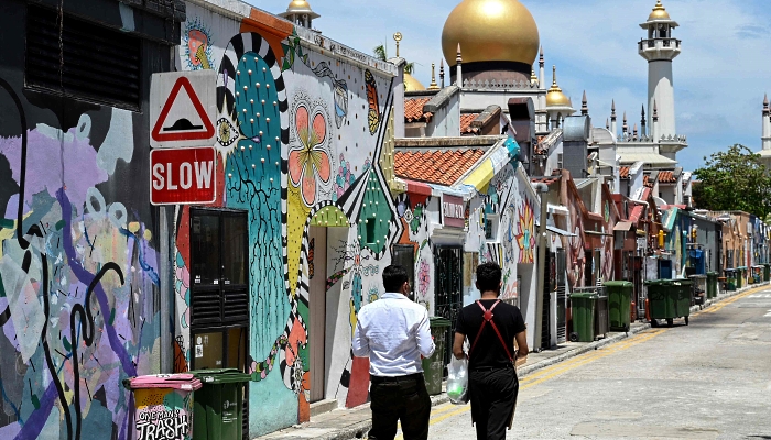 People walk past murals painted on the walls of a back lane in Singapore. AFP