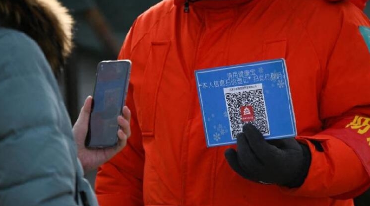 A woman using her mobile phone to scan a QR code for health registration before entering an outdoor ice rink in Beijing. AFP