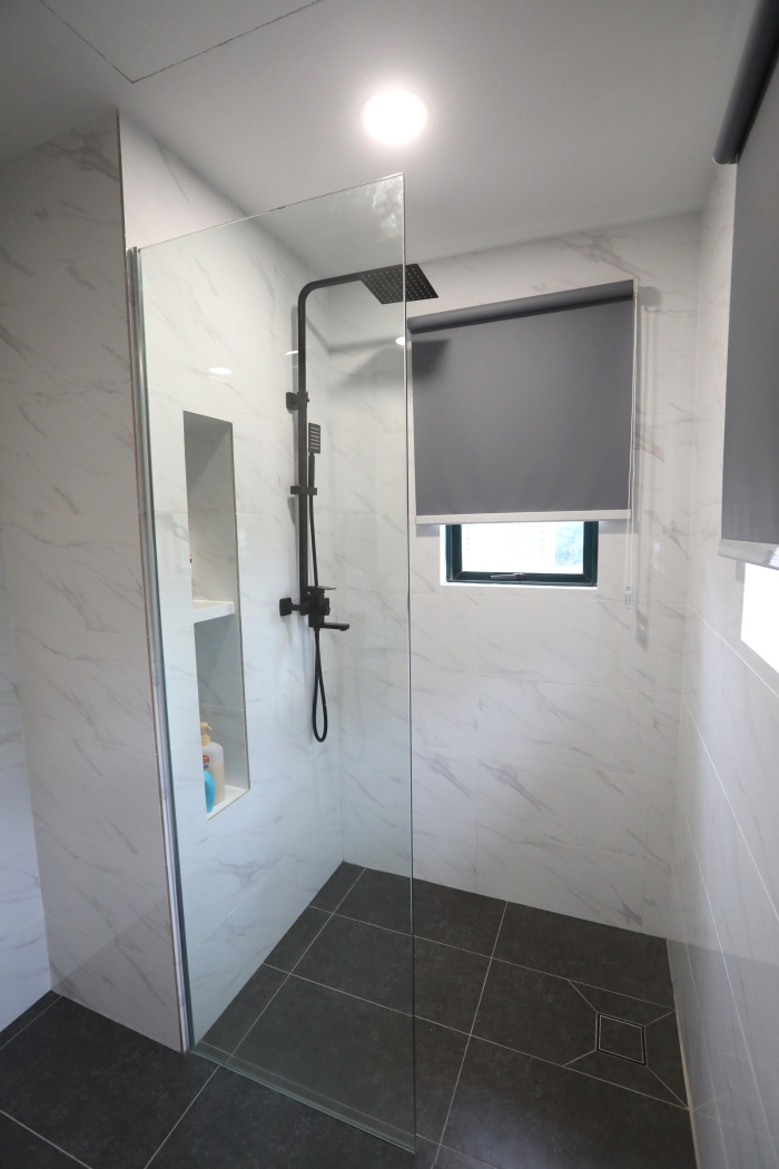 设计师将主人房浴室的浴缸拆除，将墙壁铺平，利用修饰空间打造一个摆放沐浴用品的空间。